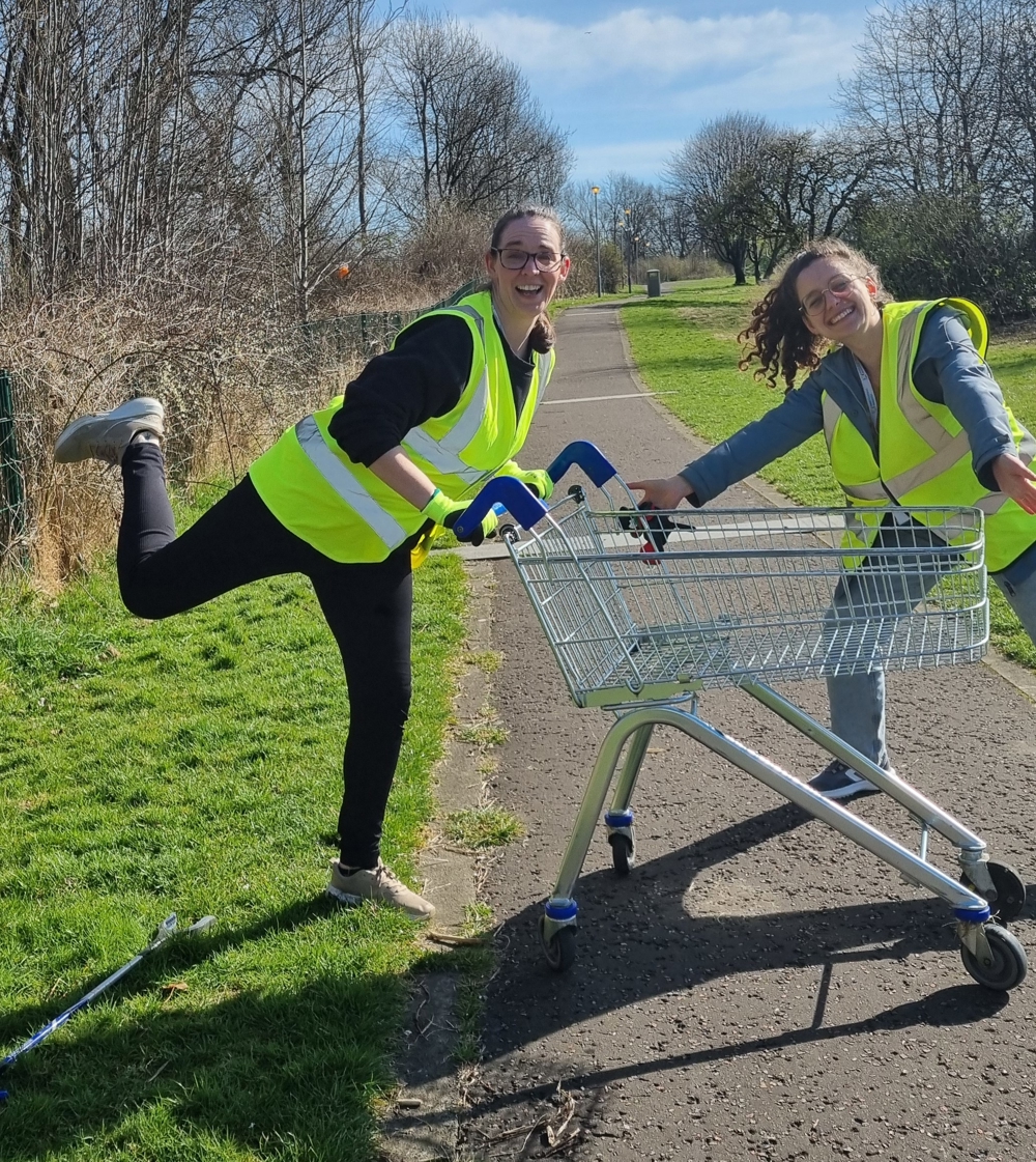 Two people pose with a shopping trolley found on a litter pick